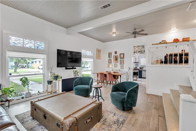 living area featuring light wood-style floors, a ceiling fan, and stairway