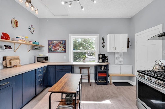 kitchen featuring blue cabinetry, appliances with stainless steel finishes, light wood-style flooring, light countertops, and open shelves