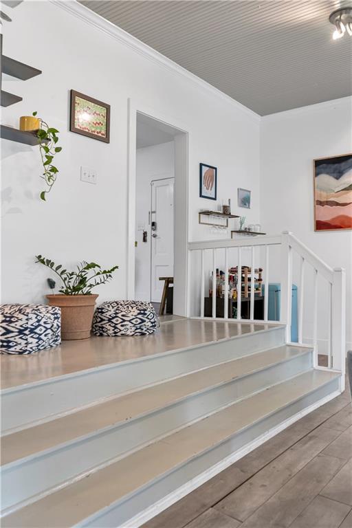 staircase featuring crown molding and wood finished floors