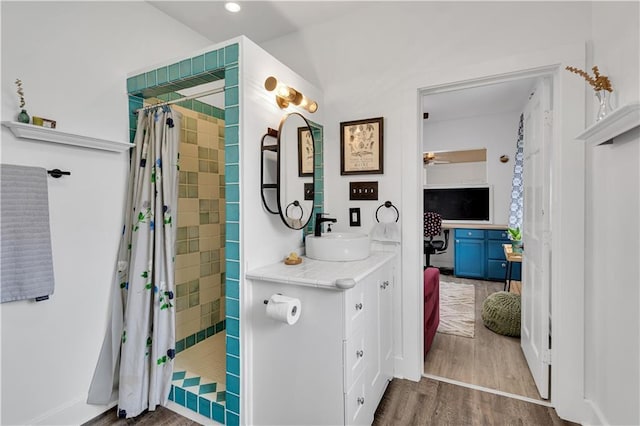 full bathroom featuring wood finished floors, tiled shower, vanity, ceiling fan, and recessed lighting