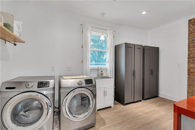 washroom featuring independent washer and dryer, brick wall, light wood-style floors, cabinet space, and baseboards