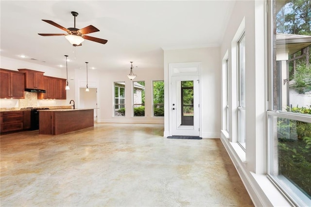 kitchen featuring under cabinet range hood, light countertops, a wealth of natural light, and decorative light fixtures