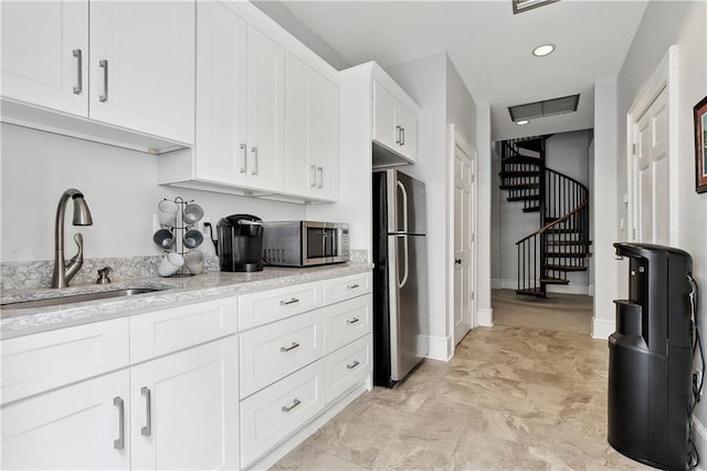 kitchen featuring light stone counters, visible vents, a sink, white cabinets, and appliances with stainless steel finishes