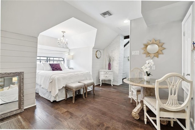 bedroom with dark wood finished floors, visible vents, wood walls, a chandelier, and lofted ceiling