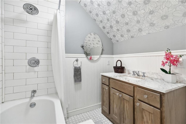 full bathroom featuring shower / bath combination with curtain, vanity, vaulted ceiling, and a wainscoted wall