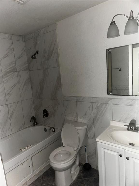 bathroom with vanity, toilet, tile walls, and shower / tub combination