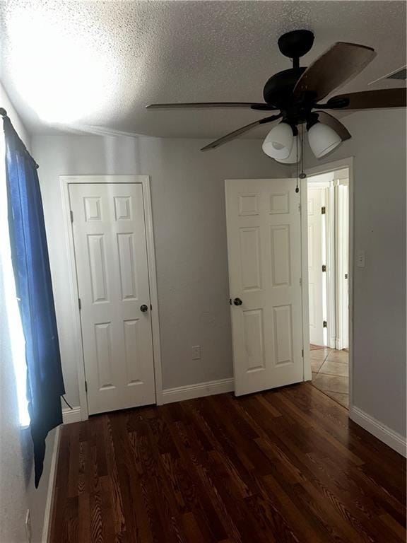 unfurnished bedroom with a ceiling fan, baseboards, a textured ceiling, and wood finished floors