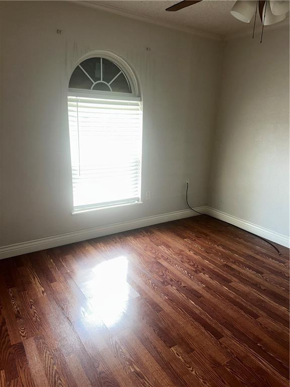empty room with baseboards, ceiling fan, and wood finished floors