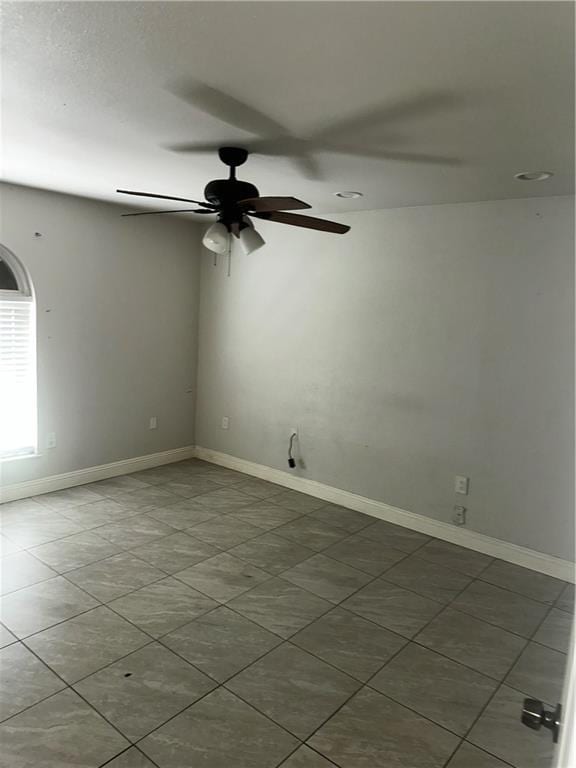 unfurnished room with a ceiling fan, baseboards, and tile patterned flooring