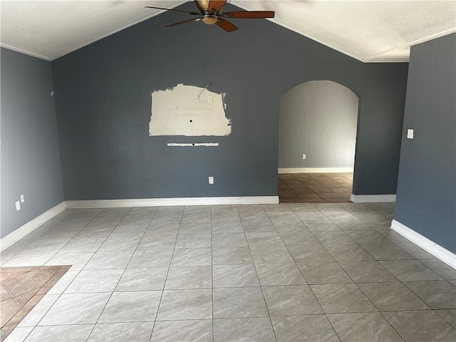 empty room with tile patterned floors, vaulted ceiling, ceiling fan, crown molding, and arched walkways