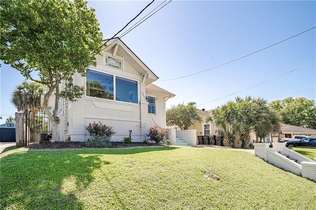 view of front of property featuring brick siding, a front lawn, and fence