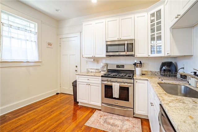 kitchen with stainless steel appliances, wood finished floors, a sink, white cabinetry, and recessed lighting