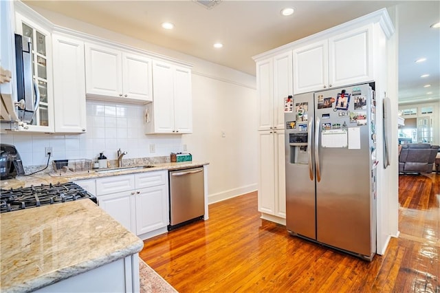 kitchen featuring stainless steel appliances, a sink, light wood-type flooring, white cabinetry, and recessed lighting