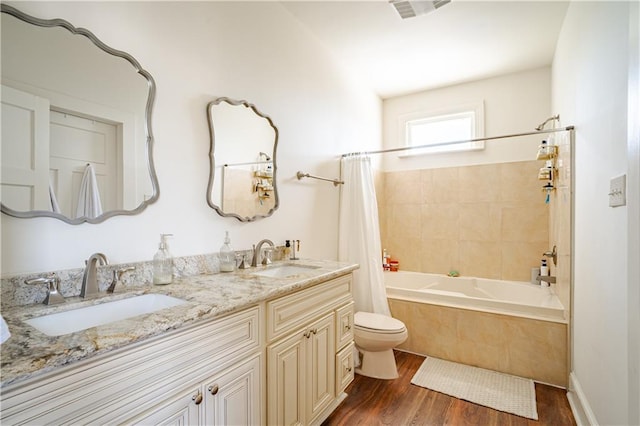 bathroom with toilet, wood finished floors, shower / bath combo with shower curtain, and double vanity