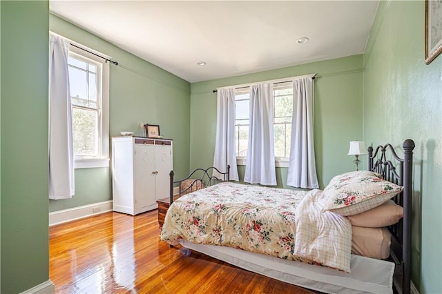 bedroom featuring wood finished floors, baseboards, and multiple windows