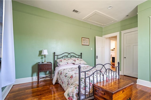 bedroom featuring attic access, wood-type flooring, and baseboards