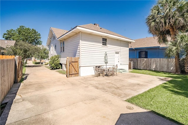 rear view of house with a lawn, a patio, and fence
