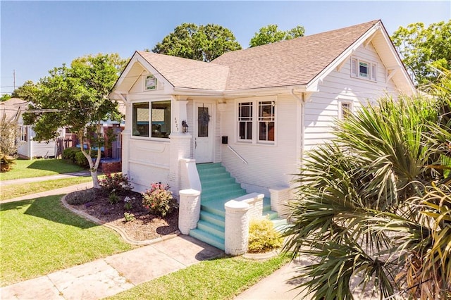 bungalow-style house with a front yard and a shingled roof