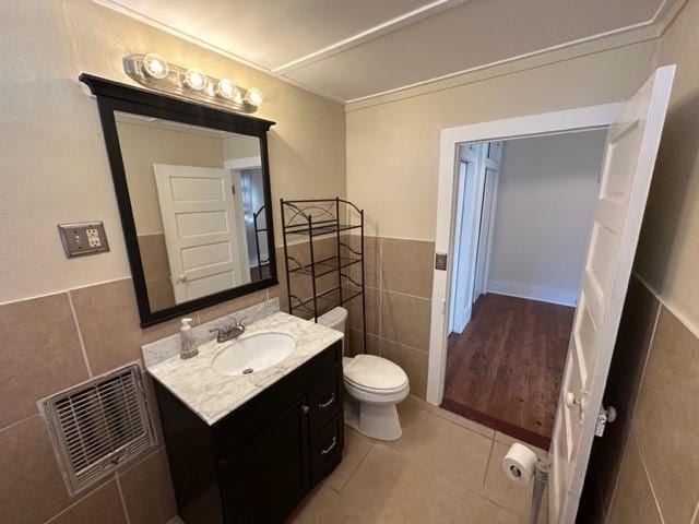 526 Bellecastle St, New Orleans, LA 70115 - bathroom featuring tile walls, tile patterned flooring, vanity, toilet, and a wainscoted wall