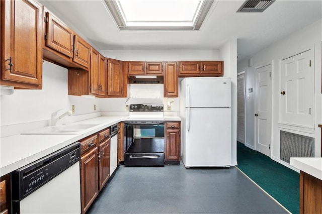 kitchen with a sink, dark floors, visible vents, white appliances, and light countertops