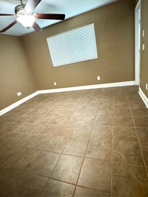 tiled spare room featuring baseboards and ceiling fan