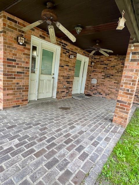 view of exterior entry featuring a ceiling fan and brick siding
