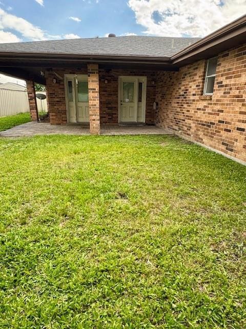back of property with a yard, a patio, and brick siding