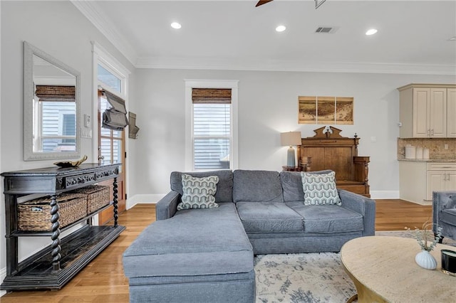 living room with visible vents, baseboards, light wood-style floors, ornamental molding, and recessed lighting