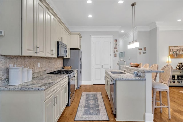 kitchen featuring light wood finished floors, a breakfast bar area, a sink, stainless steel appliances, and a kitchen island with sink