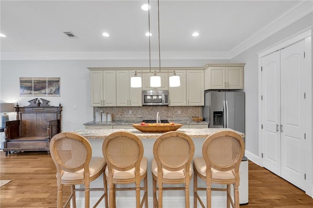 kitchen with visible vents, a kitchen breakfast bar, a kitchen island, tasteful backsplash, and appliances with stainless steel finishes
