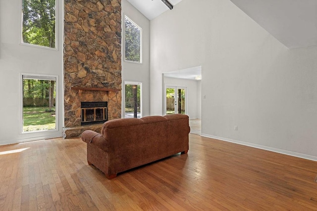 living room with a fireplace, baseboards, hardwood / wood-style floors, and high vaulted ceiling