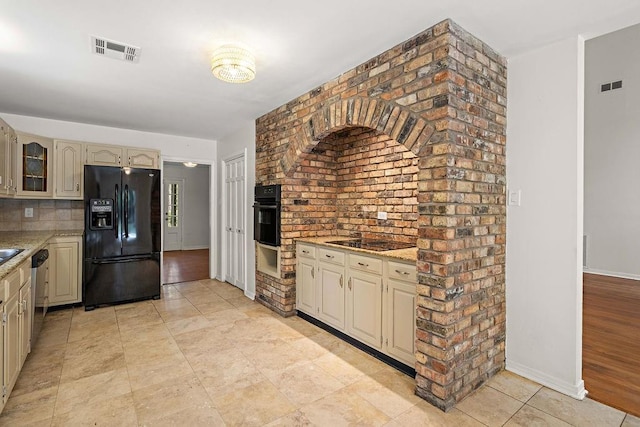 kitchen featuring decorative backsplash, visible vents, cream cabinets, and black appliances
