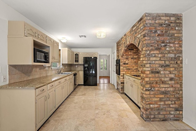 kitchen with cream cabinetry, tasteful backsplash, black appliances, and a sink