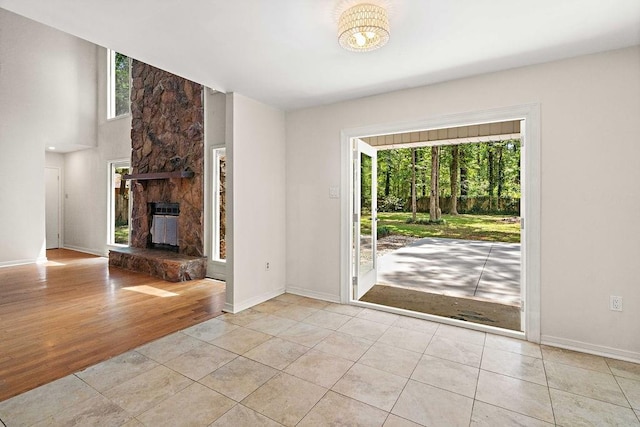 tiled foyer with a wealth of natural light, baseboards, and a stone fireplace