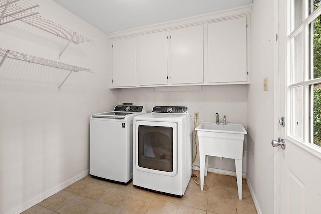 clothes washing area with light tile patterned floors, a sink, cabinet space, baseboards, and independent washer and dryer