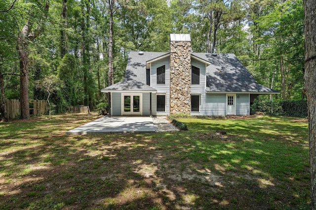 rear view of property featuring a yard, a chimney, french doors, fence, and a patio area