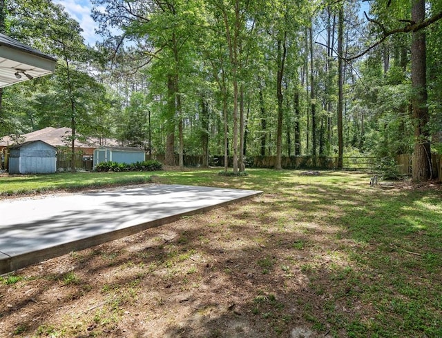 view of yard featuring an outbuilding, fence, a storage unit, and a patio