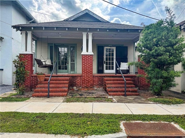 view of front of home featuring a porch, brick siding, and a shingled roof