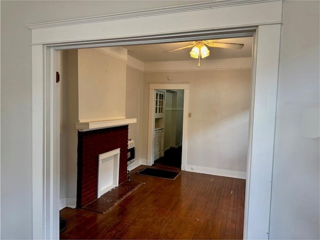 unfurnished living room with hardwood / wood-style flooring, a brick fireplace, baseboards, and ceiling fan