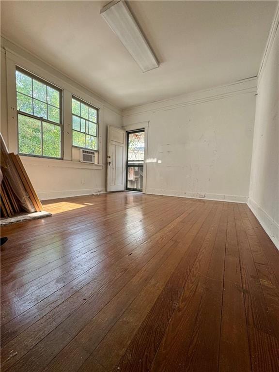 unfurnished room with hardwood / wood-style floors, crown molding, cooling unit, and baseboards