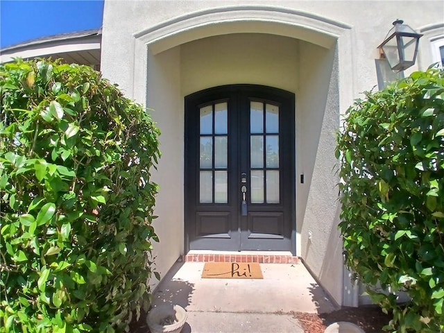 entrance to property featuring stucco siding and french doors