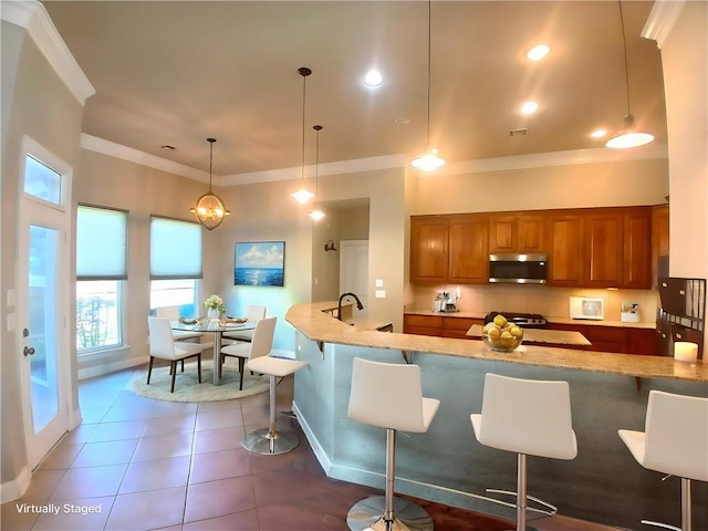 217 Turning Leaf Ln, Madisonville, LA 70447 - kitchen with brown cabinets, ornamental molding, tile patterned floors, baseboards, and a breakfast bar area