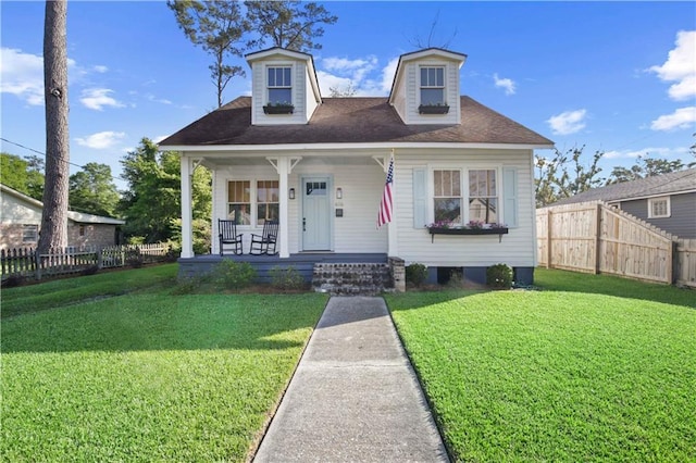 view of front of home with a porch, fence, and a front lawn