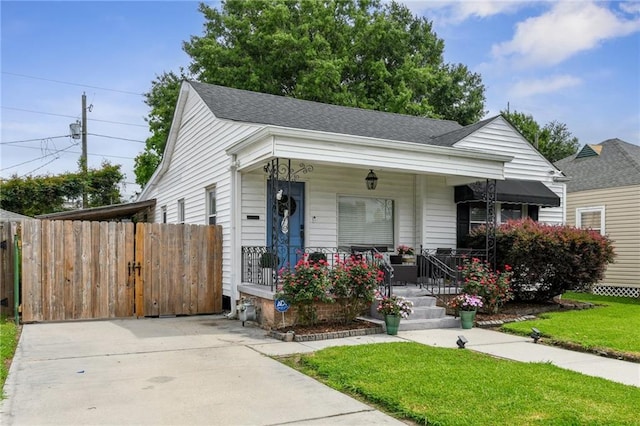 view of front of house with a porch, fence, a shingled roof, and a front lawn