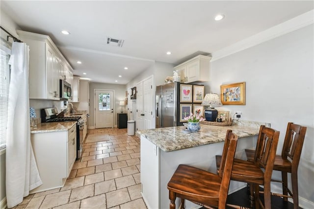 kitchen featuring a peninsula, stainless steel appliances, a kitchen breakfast bar, visible vents, and recessed lighting