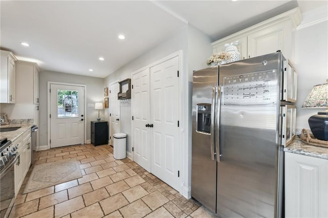 kitchen with a sink, stainless steel appliances, light stone countertops, and recessed lighting
