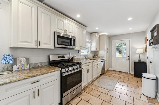 kitchen with a sink, white cabinets, light stone countertops, appliances with stainless steel finishes, and recessed lighting