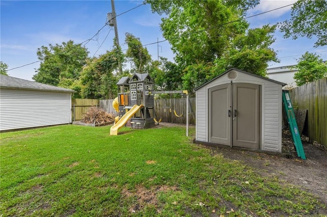 view of yard featuring a storage shed, a playground, and a fenced backyard