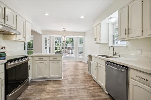 68 Begonia Dr, Covington, LA 70433 - kitchen with a sink, a peninsula, light wood-type flooring, under cabinet range hood, and appliances with stainless steel finishes