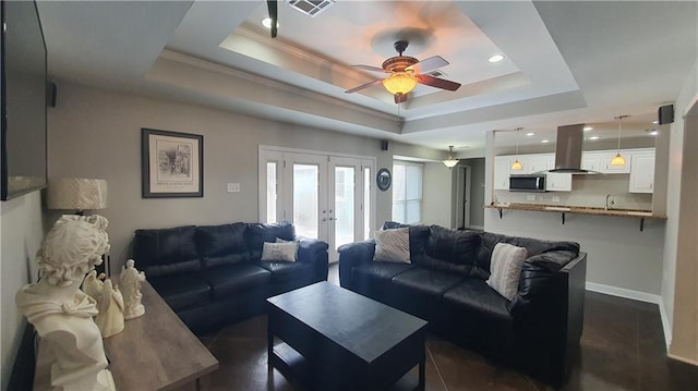 living area with french doors, a raised ceiling, ceiling fan, recessed lighting, and ornamental molding
